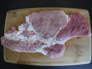 Tahta arka planda çiğ domuz pirzolası.