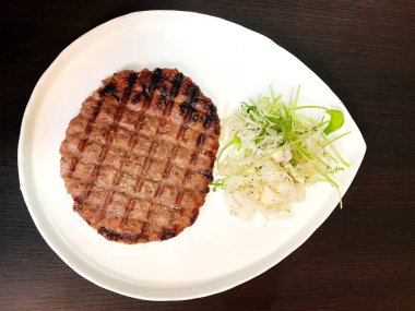 pleskavitsa cutlet and fresh vegetable salad on a white plate
