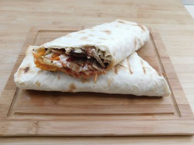 Ev konseptinde mutfak masasında tavuk dürümü pişirme süreci. Ev yapımı kebap yakın çekim. Taze lavaş ya da içinde besleyici maddeler olan bir rulo shawarma sandviçi..