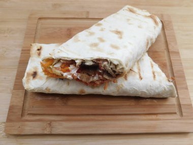 Ev konseptinde mutfak masasında tavuk dürümü pişirme süreci. Ev yapımı kebap yakın çekim. Taze lavaş ya da içinde besleyici maddeler olan bir rulo shawarma sandviçi..