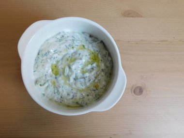 Tahta bir masada seramik tabakta Yunan tzatziki sosu