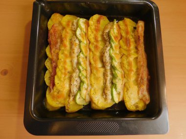 Tavuklu haşlanmış patates, kabak ve ahşap bir masada pastırma.