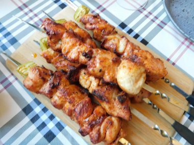 Ahşap bir masada kızarmış tavuk şişi..