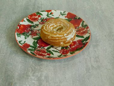 Kremalı taze organik simit ve tabakta pudra şekeri.