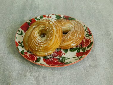 Kremalı taze organik simit ve tabakta pudra şekeri.