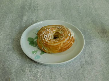 Kremalı taze organik simit ve tabakta pudra şekeri.