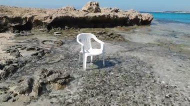 Suda beyaz plastik bir plaj sandalyesi oturuyor. Kıbrıs. Ayia Napa.