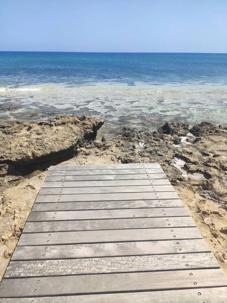 Houten pad naar de zee tegen de blauwe lucht. Protara 's. Cyprus. April 2021 — Stockfoto