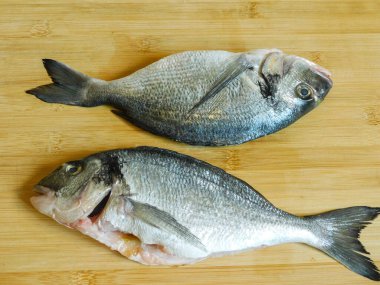 Ahşap bir masada pişmeye hazır iki dorados.