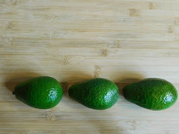 Tres Aguacates Verdes Frescos Yacen Sobre Una Mesa Madera Aguacates —  Fotos de Stock