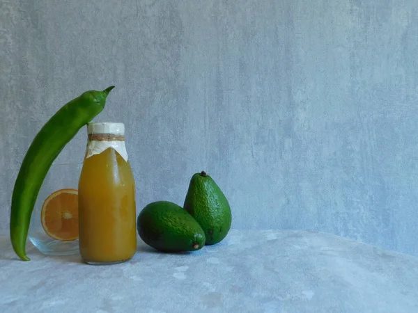 Бутылка Апельсинового Сока Авокадо Зеленый Длинный Перец Половина Апельсина Столе — стоковое фото