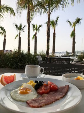 Sahildeki otelin terasında jambonlu çırpılmış yumurta ve kahve kahvaltısı. Protaras. Ayia Napa. Kıbrıs
