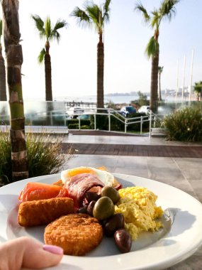Sahildeki otelin terasında jambonlu çırpılmış yumurta ve kahve kahvaltısı. Protaras. Ayia Napa. Kıbrıs