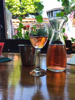 Bir bardak gül şarabı ve ahşap bir masada bir sürahi şarap. Balchik. Bulgaristan