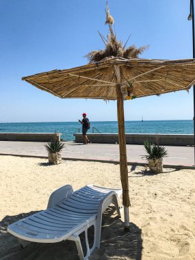 Kumlu bir sahilde şemsiyesi olan boş bir güneş yatağı. Balchik. Bulgaristan