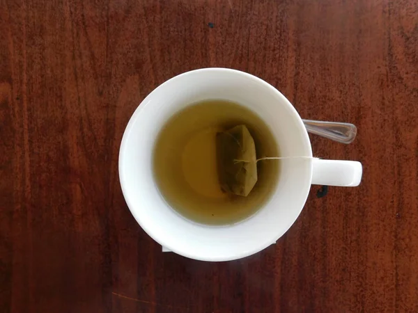 Chá verde em uma xícara branca em uma mesa de madeira. — Fotografia de Stock