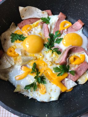 Jambonlu sahanda yumurta ve tavada otlar.