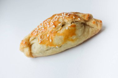 İzole edilmiş taze ev yapımı pirozhok (pirozhki), tuzlu veya tatlı dolgulu geleneksel Rus ve Ukrayna pastası) ve beyaz arka planda susam tohumları 