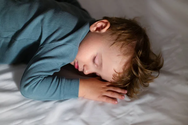 Adorable niño está durmiendo y soñando en su cama en la oscuridad en casa. — Foto de Stock