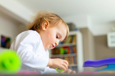 Küçük mutlu çocuk masada oturuyor ve renkli kil oyuncaklarla oynuyor. Koronavirüs karantinası sırasında evde plastikinden modellik yapan genç bir çocuk..