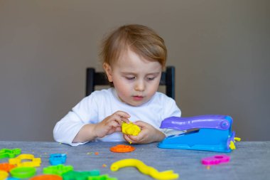 Küçük çocuk plaksin, hamur, renkli modelleme bileşimi evde ya da anaokulunda masada oturuyor. Çocuklarla yaratıcı eğlence..