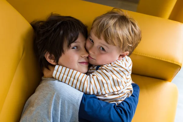 Δύο Αδέλφια Αγκαλιάζονται Και Αγκαλιάζονται Καθισμένοι Κίτρινο Καναπέ Εσωτερικούς Χώρους — Φωτογραφία Αρχείου