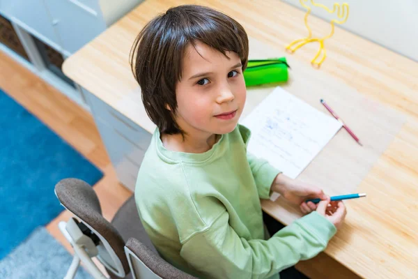 少年は宿題をして家のテーブルに座っている 集中した子供の執筆練習は喜びと ホームスクーロン教育 — ストック写真
