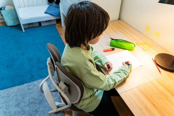 Giovane Scolaretto Che Compiti Seduto Sulla Sedia Ortopedica Tavola Casa — Foto Stock