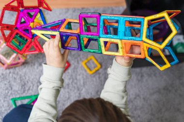 Çocuk bir odada manyetik bir yapıcıyla oynuyor. Çocuk bloklardan roket yapıyor. Çocuk renkli oyuncaklarla oynuyor..