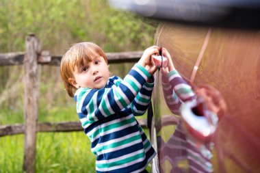 Küçük sevimli çocuk arabayı sapıyla açıyor. Çocuklarla seyahat etmek..