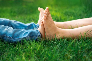 Çimenlerin üzerinde çıplak ayaklı çocuklar, yakın çekim, arkadaşlık konsepti. Kardeşler yazın birlikte parkta vakit geçirirler..