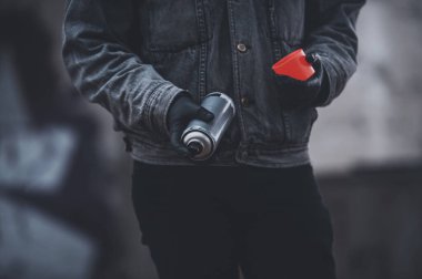 Kot ceketli adam kırmızı floresan sprey boya kullanıyor. Graffiti hazırlama süreci.