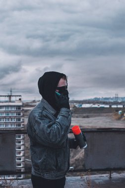Genç grafitçi sprey boya hazırlarken telefonla konuşuyor.