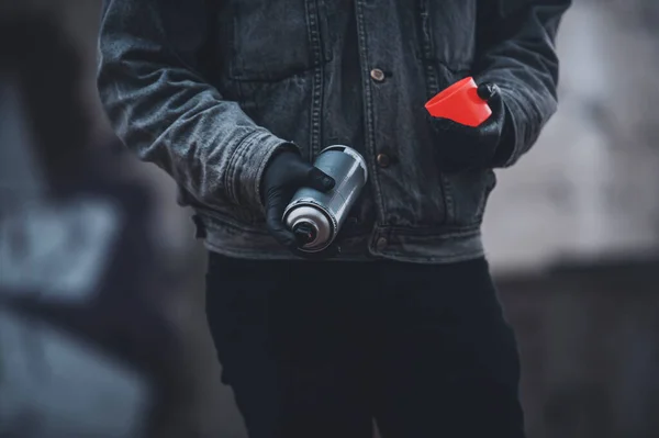 A farmerdzsekis férfi vörös fluoreszkáló festékszórót használ. Graffiti készítése. — Stock Fotó