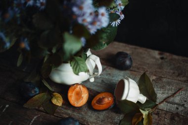 Ahşap masadaki eski moda kil vazonun yanında erik kes.