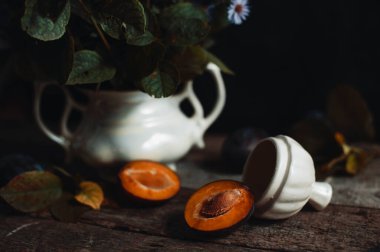 Beyaz vazonun yanındaki ahşap masada taze kesilmiş meyveler.