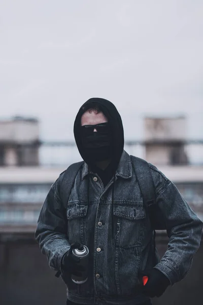 Fiatal névtelen graffitista elrejti arcát maszkkal, csuklyával és szemüveggel. — Stock Fotó