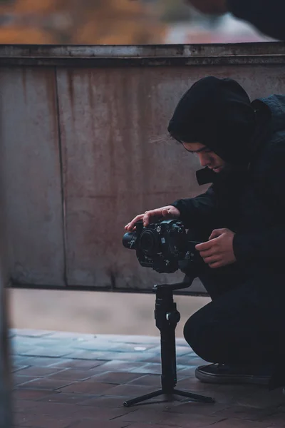 Молодой оператор в капюшоне снимает на камеру с ножом на крыше заброшенного дома — стоковое фото