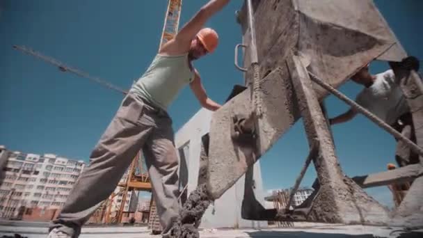 Bauarbeiter verschieben Container mit Beton und gießen ihn auf die Baustelle — Stockvideo