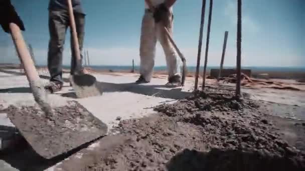 Werknemers nivelleren cement met een schop op een bouwplaats — Stockvideo