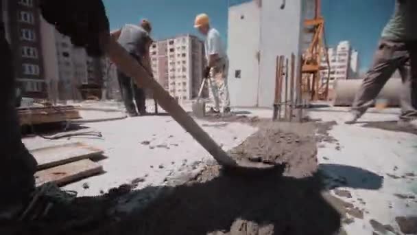 Werknemer gebruikt schep om beton op fundering van huis te nivelleren — Stockvideo