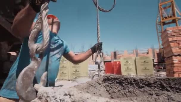 Строитель прикрепил крюк к бетонному контейнеру и поднял его с помощью крана — стоковое видео