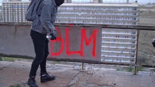 Manifestante anonimo nascosto dopo aver fatto graffiti BLM sul muro — Video Stock