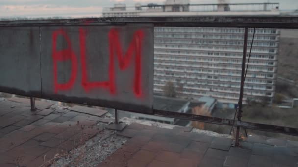 Çatının kenarına asit kırmızısı boya ile boyanmış BLM imzası — Stok video
