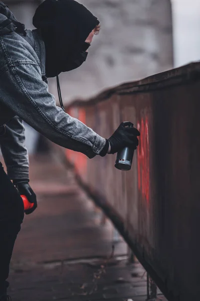 Genç anonim graffiticinin kırmızı boyalı protesto grafitisi yaparken yakın plan çekimleri.
