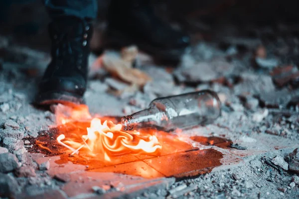 Şişenin yanında yanan gaz birikintisi. Molotof kokteyli ile ilgili talihsizlik