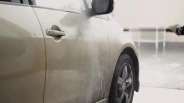 Araba yıkama işçisi bir arabayı temizlemek için yüksek basınçlı ekipman kullanır. 
