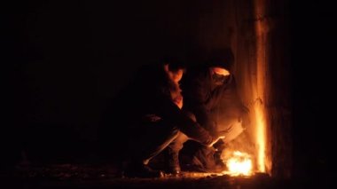 Apokaliptik görüntülerde iki zavallı evsiz adamın ellerini ateşte ısıttığı görülüyor.