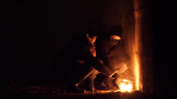 Apocalyptic footage of two young poor homeless guys heating their hand on fire — Vídeos de Stock