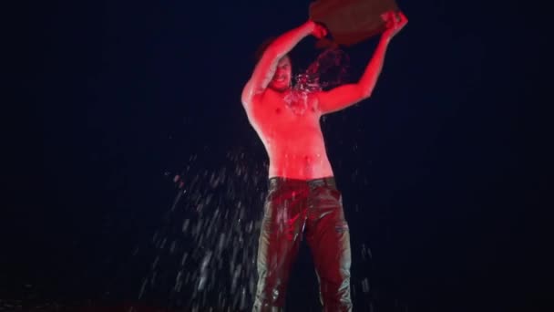 在红灯下赤身裸体的年轻人呆在煤气罐旁 — 图库视频影像
